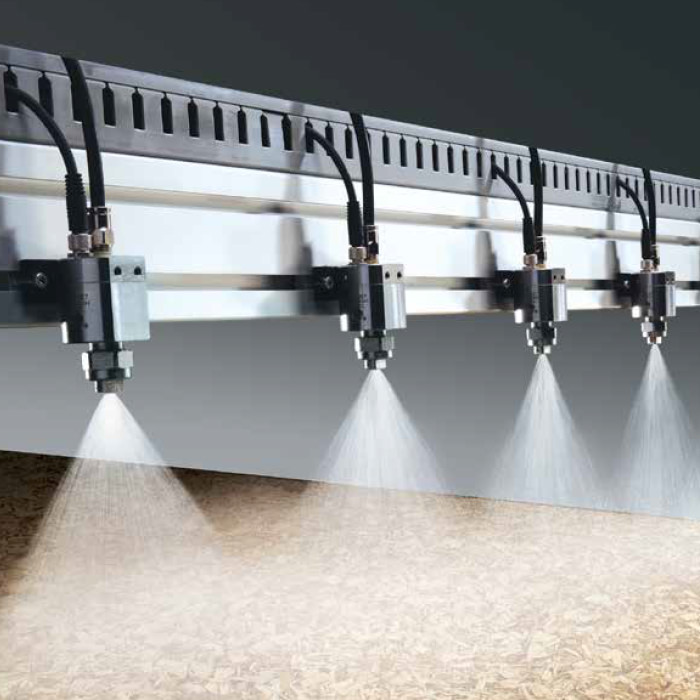 nozzles on header spraying a panel of wood